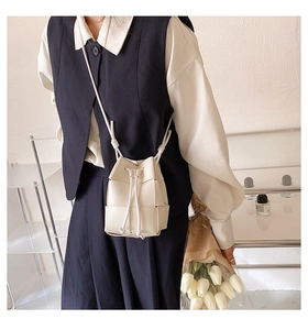 Detailed view of white woven leather bucket bag with drawstring closure on model