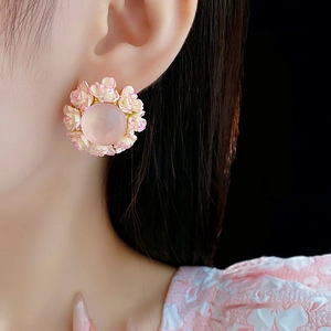Detailed side view of floral stud earring with pink gemstones on model's ear