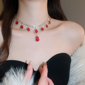 Close-up of gold necklace with red teardrop gems and rhinestones on a female model