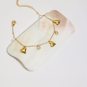 Detail of 18K gold-plated heart and zircon bracelet with lobster clasp on white tray