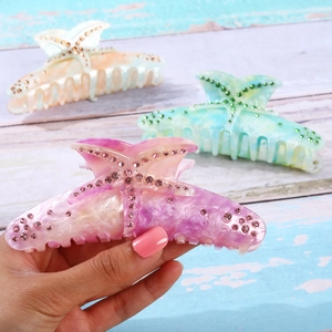 Detail of starfish hair claws with marble texture and rhinestones in soft pastel colors
