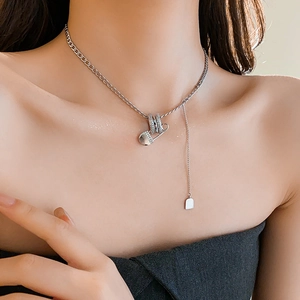 Detail of silver paperclip necklace with zircon inlay and tassel on a model