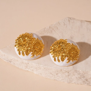 Detail shot of vintage daisy earrings with white enamel and golden floral relief on stone