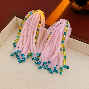 Vue macro des boucles d'oreilles à pompons roses et sarcelles sur un écrin à bijoux