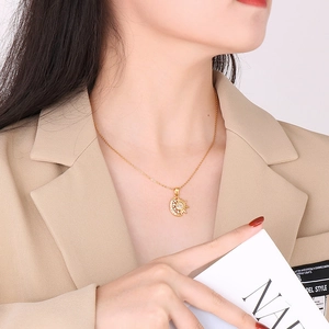 Close-up of a gold sun and moon pendant necklace with zircons worn by a model