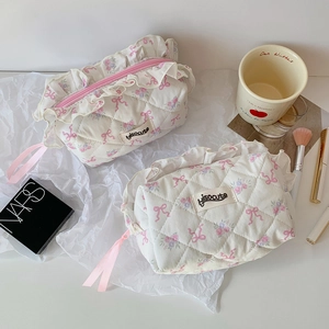Detail of quilted cosmetic bag with pink floral patterns and ruffle trim lace edges