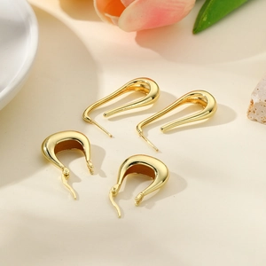 Minimalist U-shaped 18k gold plated earrings on a natural beige stone surface