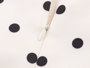 Detailed macro view of white polka dot fabric with seamless invisible zipper closure