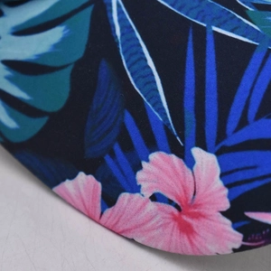 Detail of tropical floral print on navy baseball cap featuring pink hibiscus and palm leaves