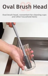 Detail of grey long-handle silicone brush cleaning the bottom of a glass cup