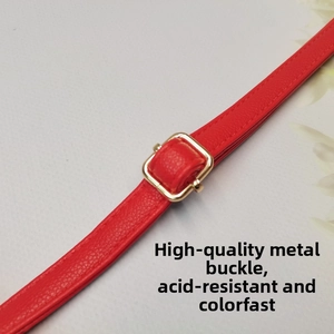 Détail macro de la bandoulière en cuir rouge grainé avec boucle réglable en métal doré