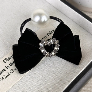 Detail of black velvet bow hair tie with rhinestone heart and white faux pearl accent