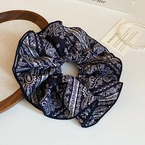 Détail d'un chouchou en tissu imprimé cachemire bleu marine sur un plateau en bois