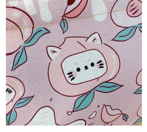 Detailed macro view of pink canvas fabric showing cat and peach patterns and woven texture