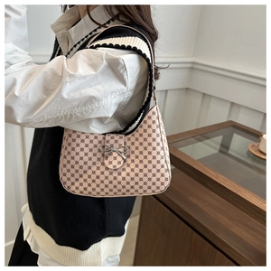 Close-up of pink hobo bag with geometric pattern and silver bow clasp on shoulder