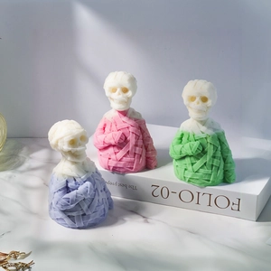 Three colorful mummy skull candles with detailed bandage texture on marble surface