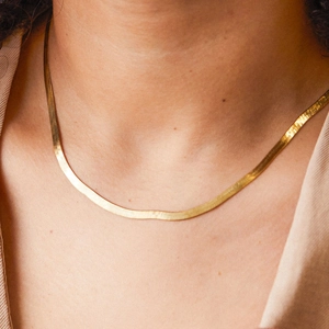 Elegant 5mm gold flat snake bone chain necklace worn by a model for a minimalist style