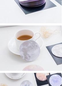 Close-up of circular planet series sticky notes on desk with handwritten reminder