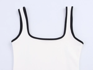 Close-up detail of white knitted vest featuring black contrast binding on the U-neck and armholes