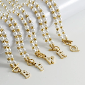 Détail de colliers de perles avec pendentifs alphabet en or 18K et fermoir à bascule