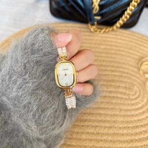 Details einer goldenen Oval-Uhr mit zweireihigem Perlenarmband und Zirkonia-Akzenten