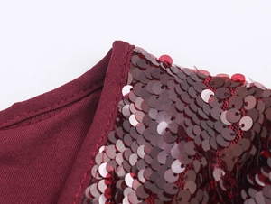 Dettaglio del tessuto con paillettes rosso vino e scollo a costine dell'abito
