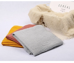 Detail of multi-colored solid voile scarves with fringed edges and crinkle texture
