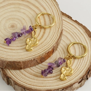 Detail of gold hoops with natural purple amethyst stones and musical note charms on wood