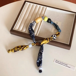 Dettaglio della collana in tessuto vintage con perle in legno e ciondolo a forma di cuore