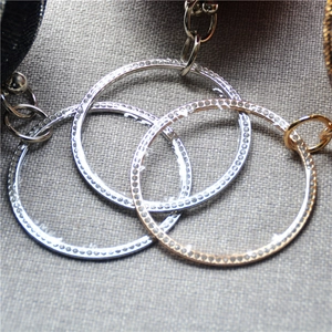 Macro detail of interlocking gold and silver rings with inlaid crystals on a chain