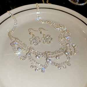 Detail of luxury gold flower jewelry set with sparkling rhinestones on a white plate