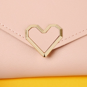 Macro shot of pink leather long wallet featuring a golden heart-shaped metal buckle detail