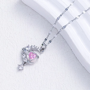 Detailed macro view of silver crescent moon and pink heart pendant with zircon inlay