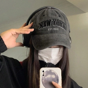 Detailed close-up of embroidered New York text on a washed grey baseball cap