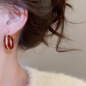Close-up of vintage burgundy hoop earrings with gold metal accents worn by a model