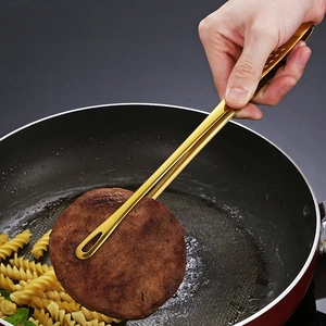 Pince à barbecue en acier doré 304 saisissant une viande dans une poêle à frire
