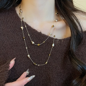 Detailed macro view of 18k gold plated double layer necklace with tiger eye and pearls
