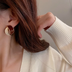 Close-up of model wearing vintage gold-edged geometric enamel earrings with white knitwear