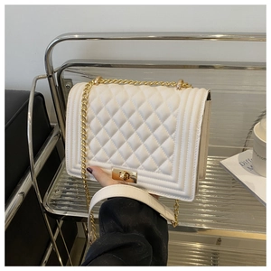 Detail of white quilted crossbody bag with golden chain strap and metallic lock closure