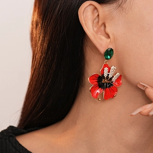 Gros plan de boucles d'oreilles fleurs vintage avec émail rouge et pierres précieuses