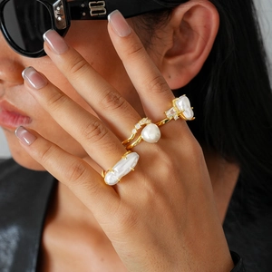 Close-up of model wearing baroque pearl and zircon layered rings in gold finish