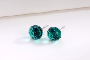 Close-up of green faceted crystal stud earrings with S925 silver needles on white background