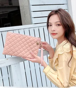 Detail of pink quilted lattice handbag with metal turn-lock and wrist strap on model