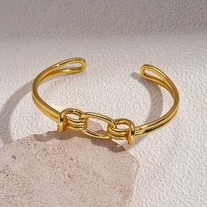 Detailed macro view of 18K gold plated knotted open bangle on elegant stone base