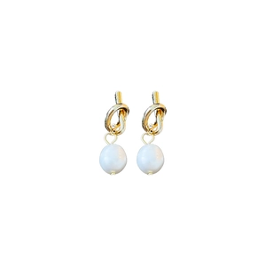 Boucles d'oreilles nœud doré avec perles d'eau douce blanches sur fond blanc élégant