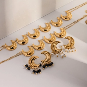 Detail of 18k gold plated moon earrings with black crystal and white pearl accents