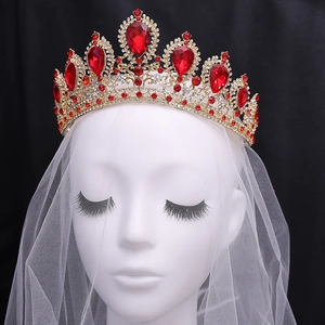 Exquisite bridal rhinestone crown with large red gemstones and white veil on a mannequin