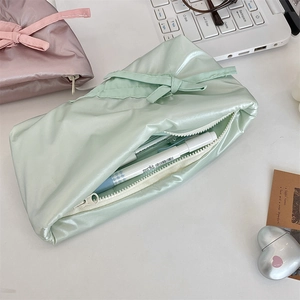Macro shot of stylish silk bow pencil cases in pastel green and dusty pink colors