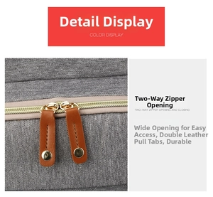 Detail view of durable dual-way metal zippers with leather pullers on a gray diaper bag