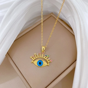 Golden evil eye necklace with colorful crystals on a beige jewelry box and white silk